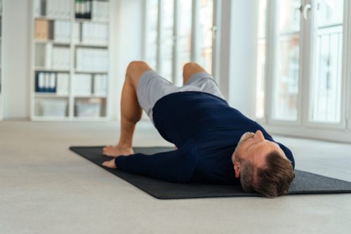 Man,Doing,Bridging,Exercise,,Lying,On,His,Back,On,Black